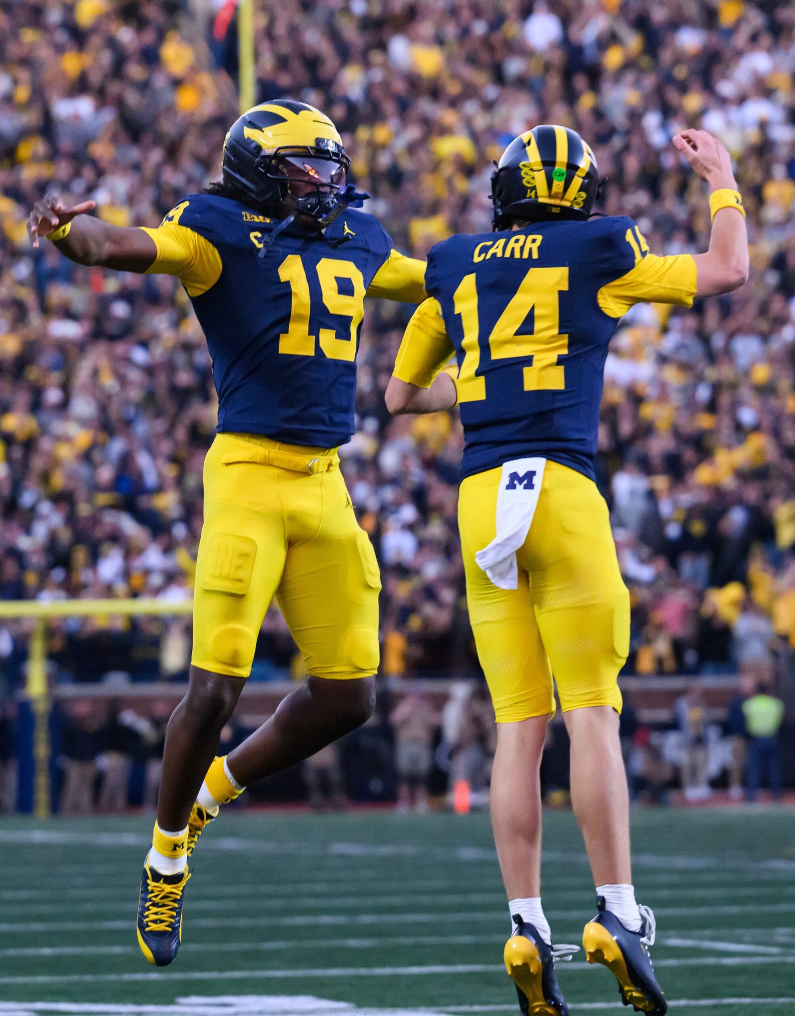 Michigan quarterback Bryce Underwood (19) leaps to congratulate freshman quarterback Tommy Carr after Carr scored on a 12-yard touchdown run to put the Wolverines ahead 21-11 after the extra point. Carr replaced the struggling starter Underwood to start the second half.